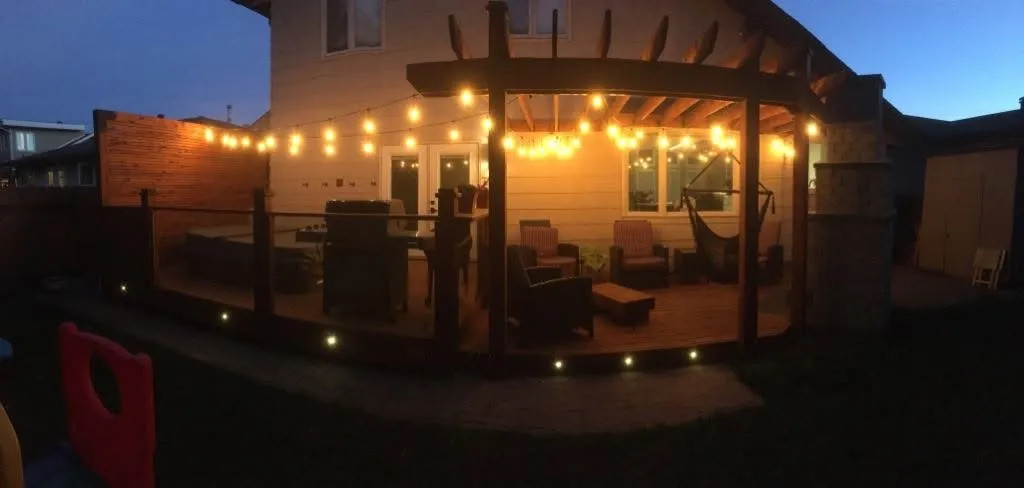 Backyard pergola and patio lit with string lights at dusk