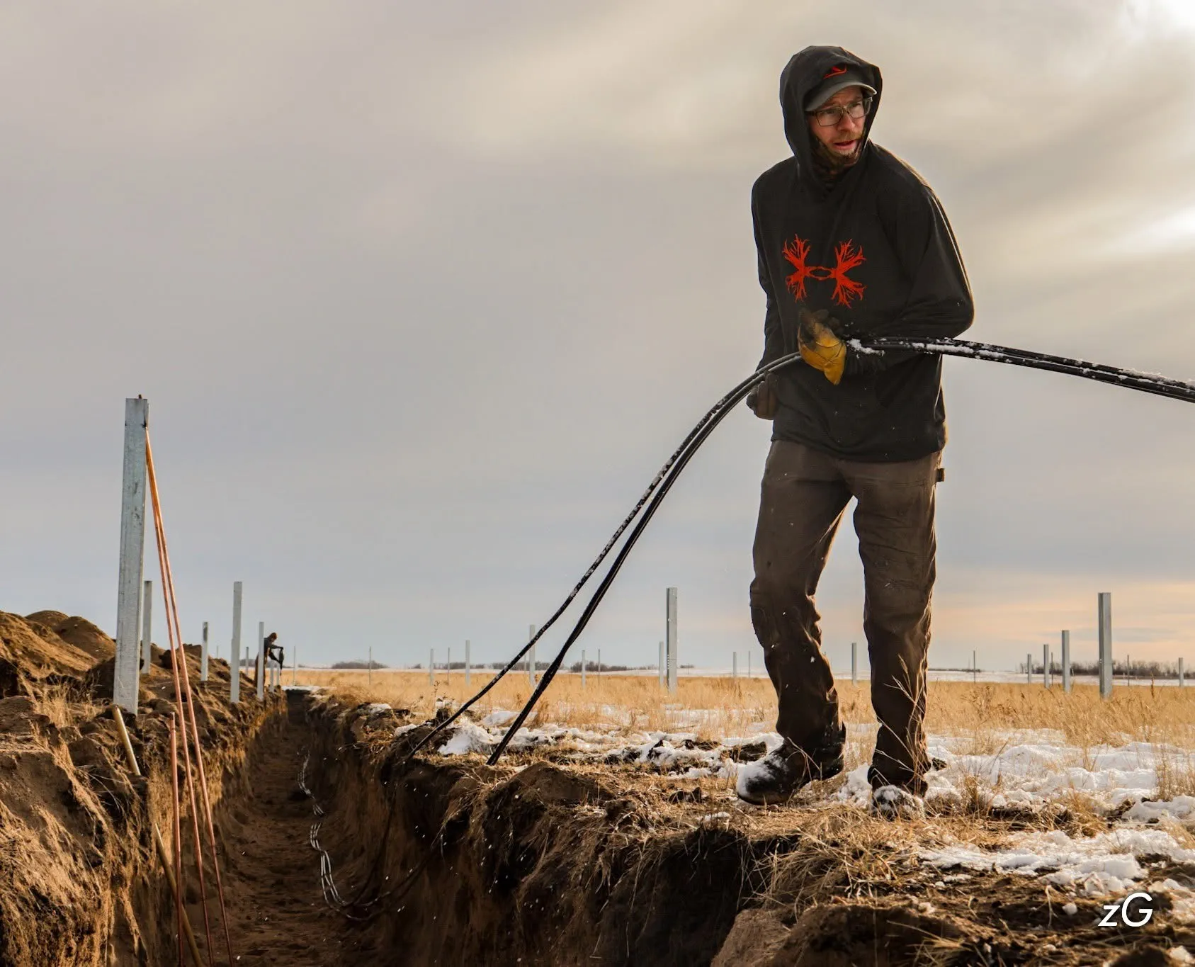 Electrician laying underground cable in a trench on a Saskatchewan farm
